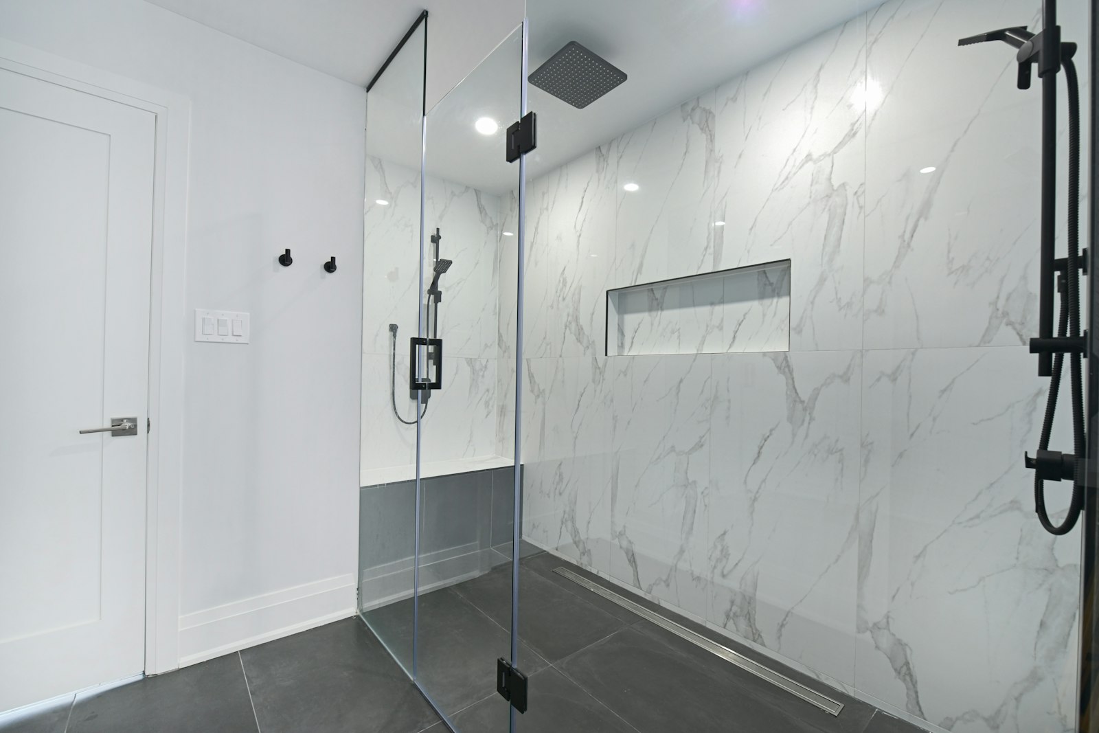 Renovated bathroom with frameless glass shower and marble tiling
